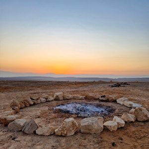 שמיים בהירים מעל אתר מדורה במדבר בשעת זריחה